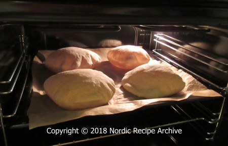 Pita breads puffing up in oven